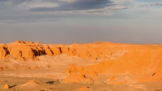 Bayanzag Flaming Cliffs, Mongolia, Omnogovi province, Gobi desert, panoramic view at sunset under a stormy sky, while tourists, with rental russian minibus, have dinner in front of their tents
