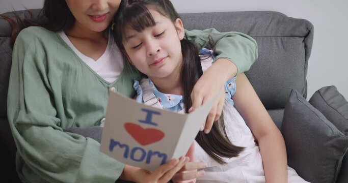 A little daughter gives a Mother's Day card to her beloved mother.