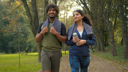 Outdoors in nature park Indian Arabian couple friends man woman walking talking walk resting after...
