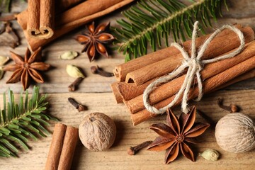 Different aromatic spices and fir branches on wooden table, closeup