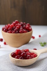 Spoon with fresh ripe cranberries on table, closeup