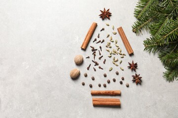 Obraz na płótnie Canvas Christmas tree made of different spices and fir branches on light gray textured table, flat lay. Space for text