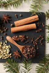 Different spices and fir branches on wooden table, flat lay