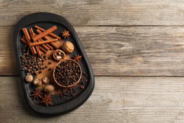 Different spices and nuts on wooden table, top view. Space for text