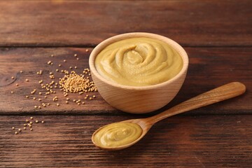 Tasty mustard sauce and dry seeds on wooden table, closeup