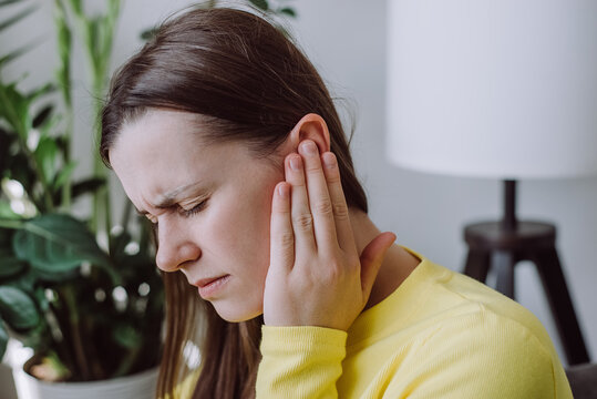 Sick sad young woman has ear pain or earache, hand touch plug ear, suffering painful otitis from loud or noisy sound, inflammation. Health care nerve deaf eardrum disease. Tinnitus concept