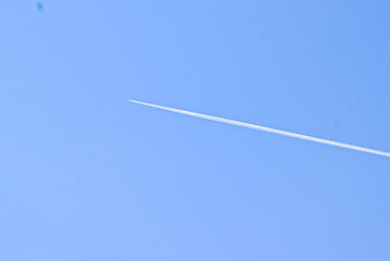 Thermal trace from a flying airplane in the middle of a clear cloudless blue sky