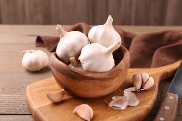 Fresh garlic and knife on wooden table, closeup
