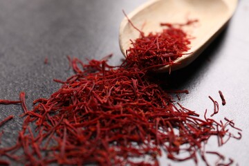 Aromatic saffron and wooden scoop on gray table, closeup
