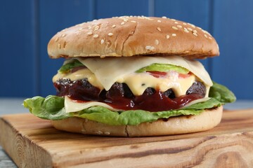 Tasty homemade cheeseburger with lettuce on wooden board, closeup