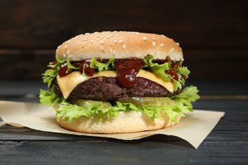 Burger with delicious patty on black wooden table