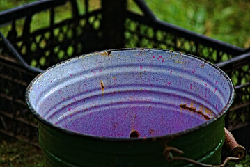 An old metal enameled bucket, with traces of potassium permanganate on the walls, after working in...