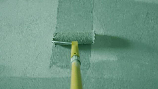 Painting Grey wall with paint roller . Close Up Shot of White Paint being applied on a wall. Room Renovations at Home concept. Painter man painting the wall in home. Camera attached to the brush