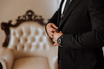 the groom's hands fasten his jacket in the morning before the wedding. close-up of a man in...