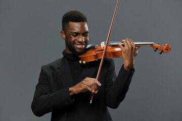 African American man playing violin on grey background, showcasing talent and passion for music