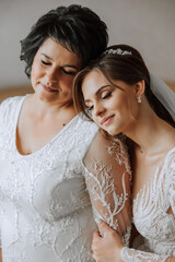 A beautiful and happy mother and her daughter, the bride, are standing next to each other. The best day for parents. Tender moments at the wedding.