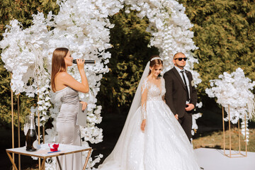 A female wedding presenter giving a speech and the bride and groom