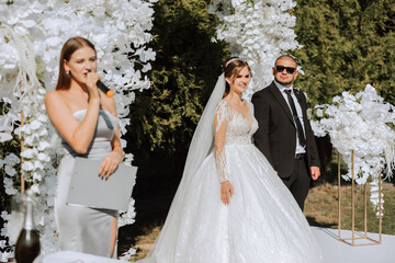 A female wedding presenter giving a speech and the bride and groom