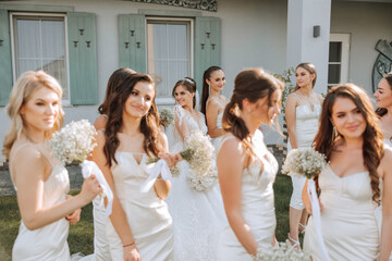 Wedding photography. Bridesmaids in beige dresses walk with bouquets of gypsophila