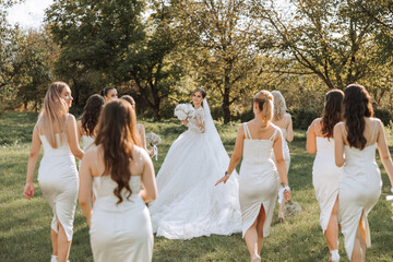 A brunette bride in a long wedding dress and her friends in beige dresses