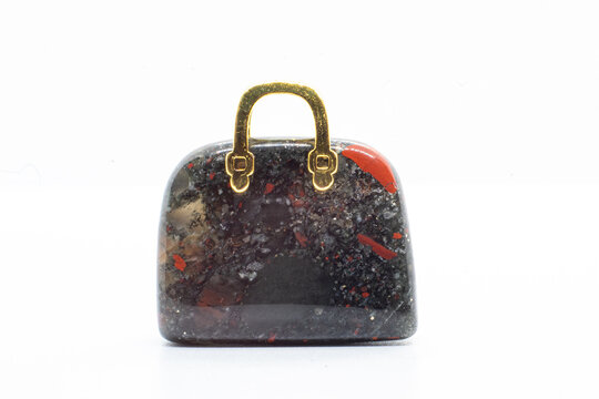 Blood stone Chalcedony, Heliotrope opaque silicate mineral, Crystal carving Bag with a gold metal handle isolated on white background surface 