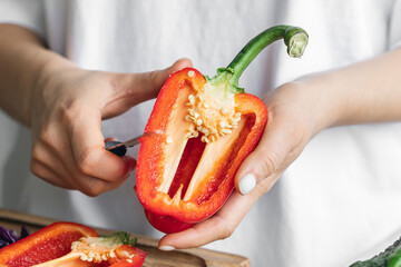 Close-up, cut bell pepper in female hands in the kitchen.