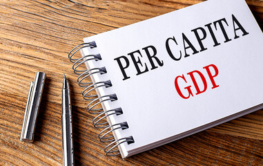Per Capita GDP text on notebook with pen on wooden background