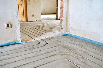Fußbodenheizung wird in Estrich eingefräst bei einer Renovierung von Einfamilienhaus. 