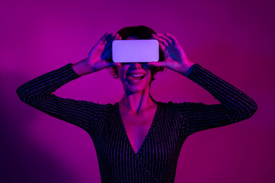 Photo portrait of lovely young lady cover eyes white screen dressed stylish overall garment isolated on neon light pink color background