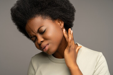 African american woman touching enlarged lymph nodes under ear on neck. Black female frowning of...