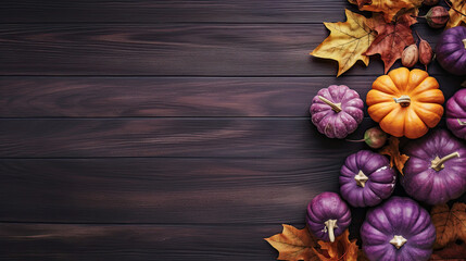 Obraz na płótnie Canvas A group of pumpkins with dried autumn leaves and twigs, on a dark purple color wood boards