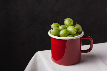 Fresh green gooseberry berries on a light background