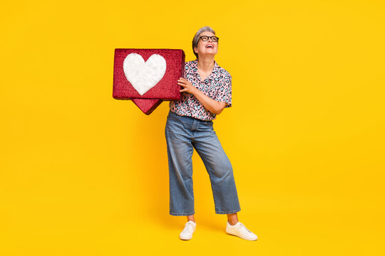 Full body photo of pensioner woman heart icon look empty space dressed stylish leopard print clothes isolated on yellow color background