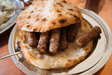 Bosnian Cevapi – the National Dish of Bosnia and Herzegovina made with minced beef and lamb and i served with onions, ajvar and somun bread