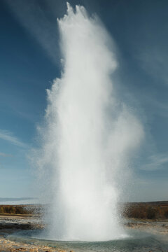Erupting Strokkur Geyser under clear blue skies in Iceland