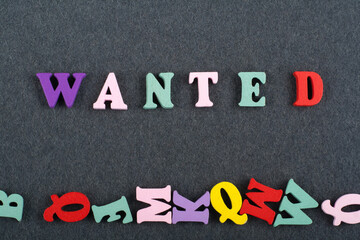 WANTED word on black board background composed from colorful abc alphabet block wooden letters,...
