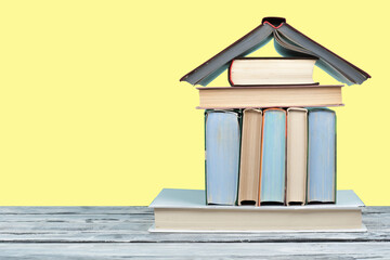 Open book, hardback colorful books on wooden table and yellow background. Back to school. Copy...
