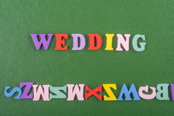 WEDDING word on green background composed from colorful abc alphabet block wooden letters, copy...