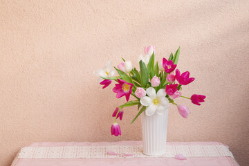 tulips in vase on table on background wall