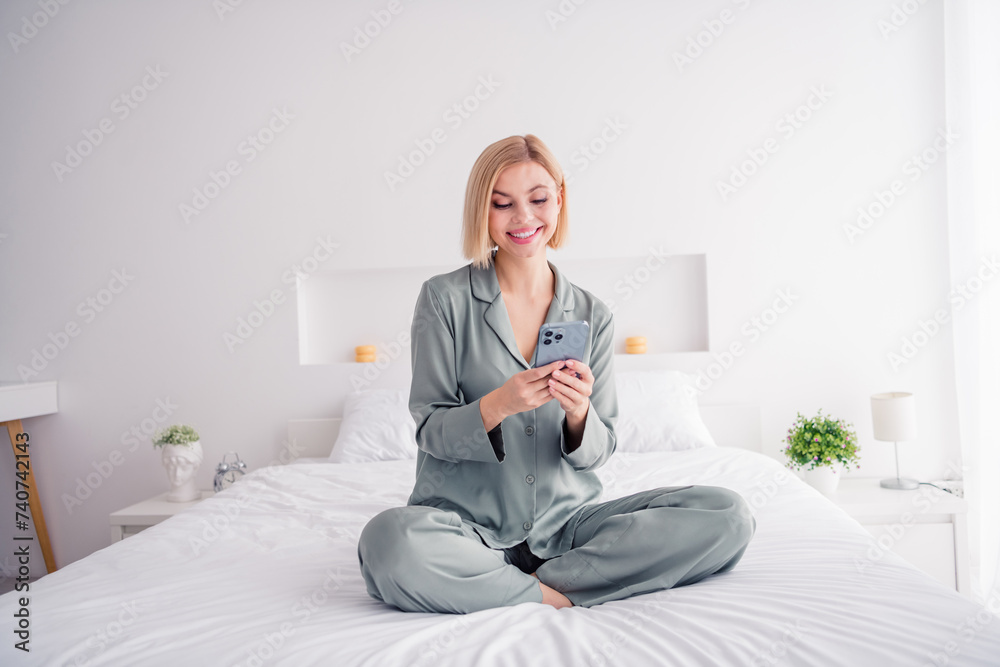 Poster Full body length photo of young lady blonde hair model sitting bed white laundry texting sms on iphone her boyfriend buy sweets indoors