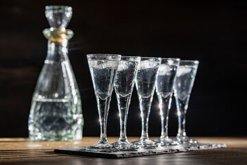 Selective focus of five shot glasses of cold vodka on wooden table, closeup