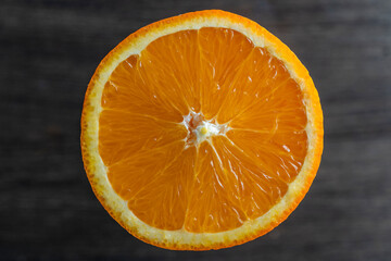 Close up of sliced ripe orange, macro. Yellow fresh orange surface on wooden background
