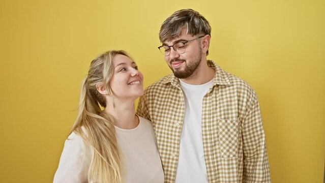 Beautiful couple confidently gesturing an 'ok' sign with their fingers, a symbol of excellent, success together. standing, smiling friendly in front of an isolated, yellow background wall
