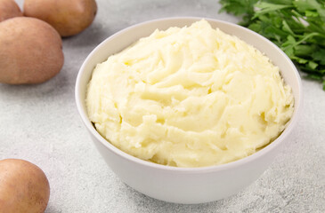 Bowl of tasty mashed potato, parsley,  and pepper on grey marble table