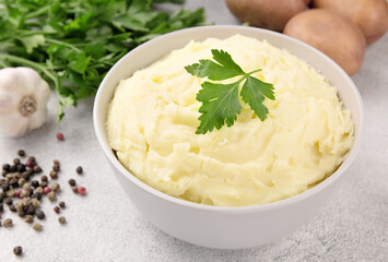 Bowl of tasty mashed potato, parsley,  and pepper on grey marble table