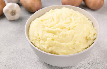 Bowl of tasty mashed potato, parsley,  and pepper on grey marble table