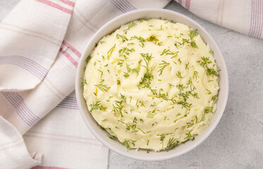 Bowl of tasty mashed potato, parsley,  and pepper on grey marble table