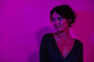 Photo portrait of pretty young girl look empty space poster wear trendy overall outfit isolated on neon light pink color background