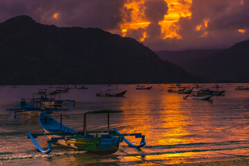 A group of colorful boats docked on a calm lake at sunset, with mountains and clouds in the background.