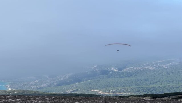 The unrecognizable paraglider flies over the mountains on a paraplane